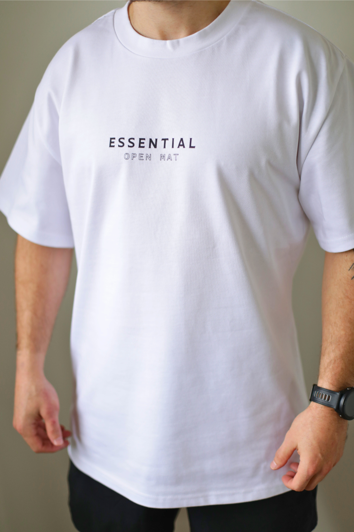 Model wearing the Open Mat Essential white t-shirt by Just Roll Threads, front view, featuring breathable fabric ideal for intense BJJ training sessions and everyday wear. Perfect for Brazilian Jiu-Jitsu (BJJ) training, competitions, and casual wear.
