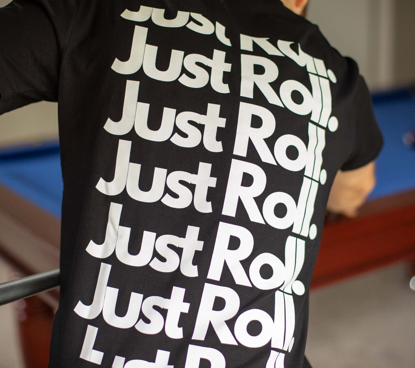 Man taking a pool shot in black and white brazilian jiujitsu t-shirt