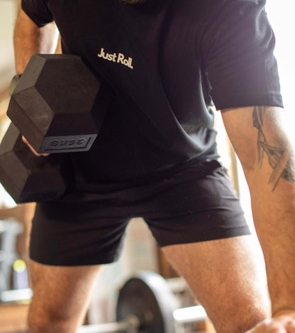 Athlete in gym, performing a dumbbell row in black and white brazilian jiujitsu t-shirt